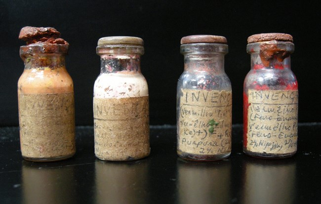 Hélio Oiticica paint samples. Four glass bottles with hand labeled paper labels and stoppers.