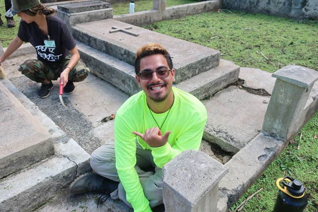 Makoa Caceres signs while he and others do conservation to grave markers at Kalaupapa National Historical Park.