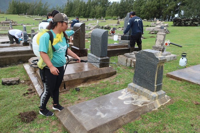 Rinsing the grave marker after cleaning with D/2. Several students rinse grave markers after they have been cleaned with D/2.