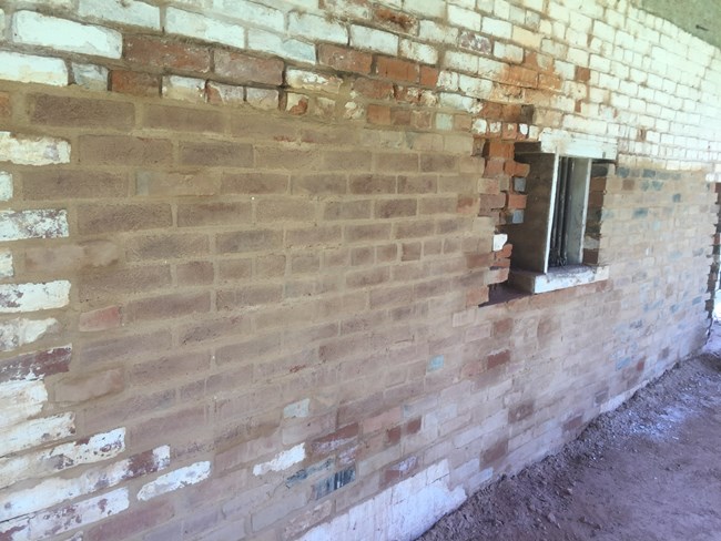 A historic wall in process of restoration by Pierre using original lime mortar.