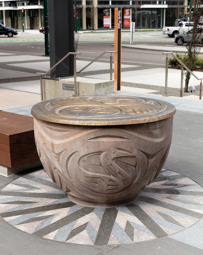 "Salish Gifts" in cast concrete with bronze lids and set on colored stone. "Salish Gifts" in cast concrete with bronze lids and set on colored stone.