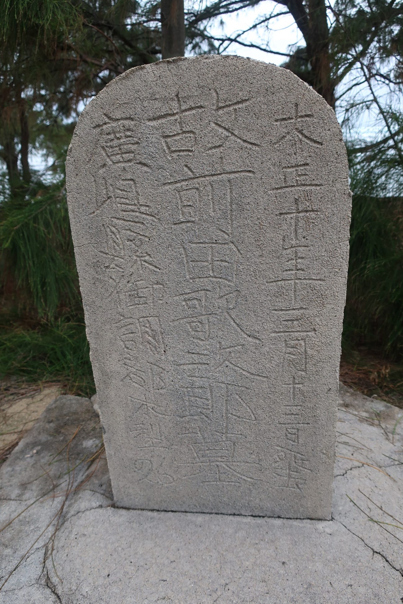 Cast concrete grave marker with finely inscribed characters.