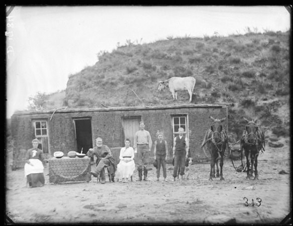 a group of settlers standing in front of a wooden shack