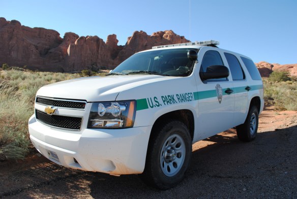 an SUV that is white with a green stripe on the side and there are police lights on top