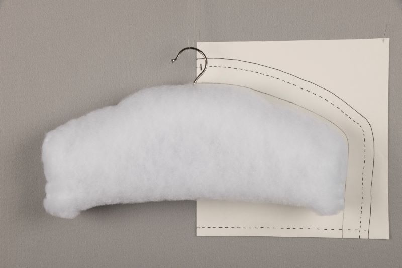 Demonstrating how to create a slipcover for a hanger from muslin.