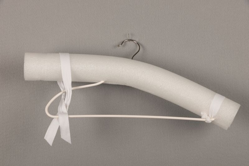 Demonstrating how to secure a white pool noodle to a hanger.