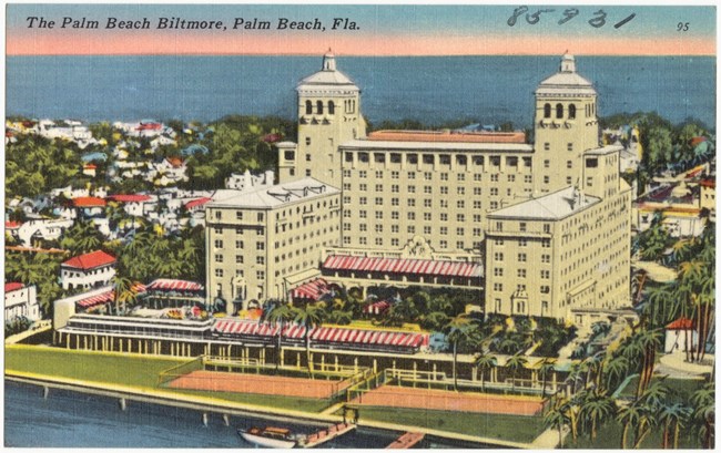 Illustrated postcard image of a tan building surrounded by palm trees with water behind and in front of it. Text reads "the Palm Beach Biltmore, Palm Beach, Fla."