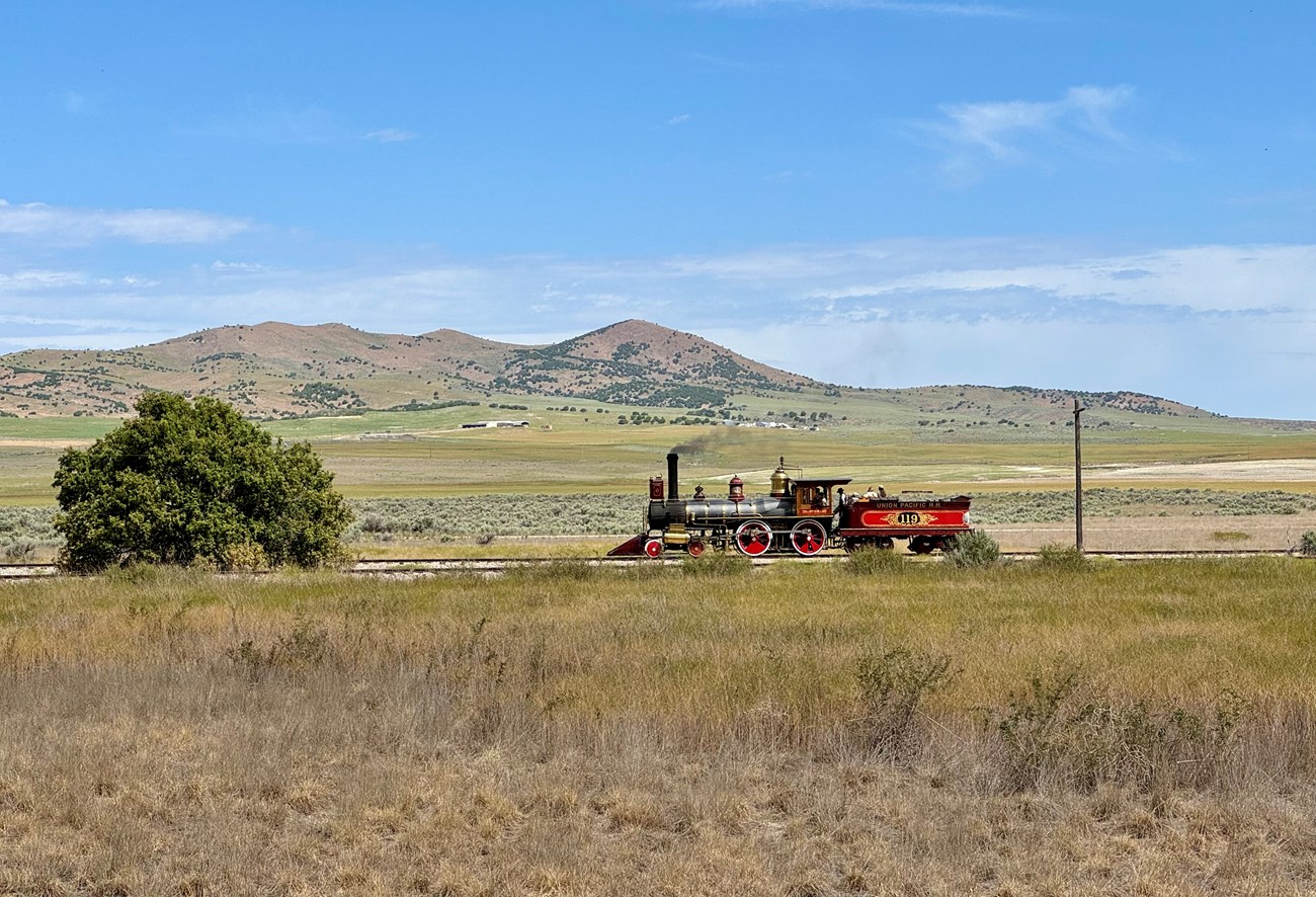 Train crosses Golden Spike NHS landscape where vegetation was studied from 2000 to 2019. Replica locomotive at Golden Spike NHP, surrounded by sagebrush, grasses, and shrubs.