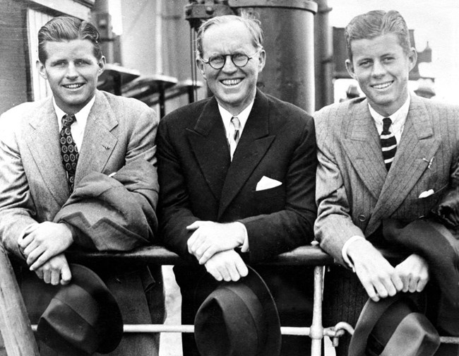 Joe Jr., Joe Sr. and John Kennedy lean on the rail of a boat.