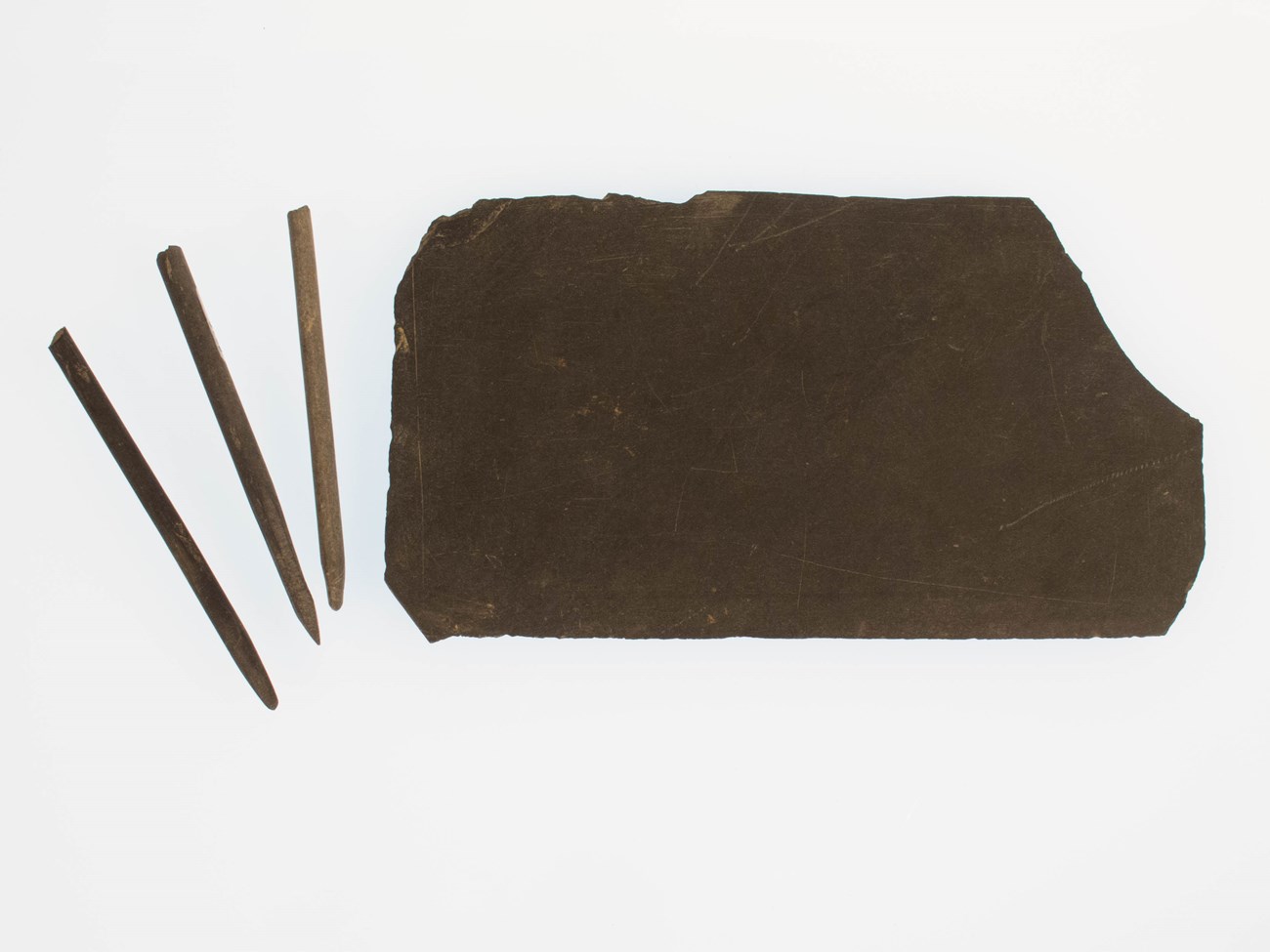 pencils and slate a large slate and three pencils arranged on a white background