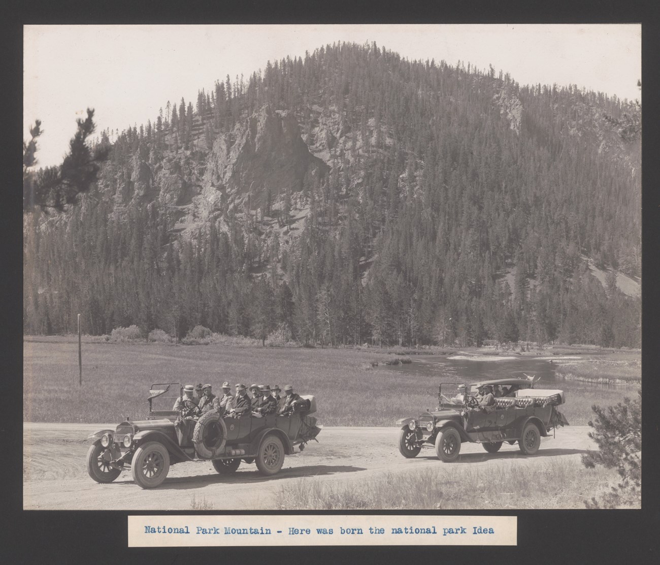 National Park Mountain Men in two old open-top touring cars in front of a mountain