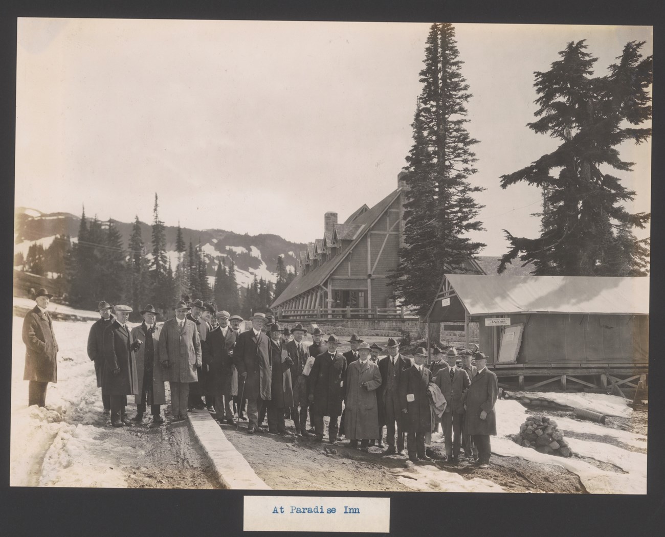 A group of men stand for a photograph with Paradise Inn behind them