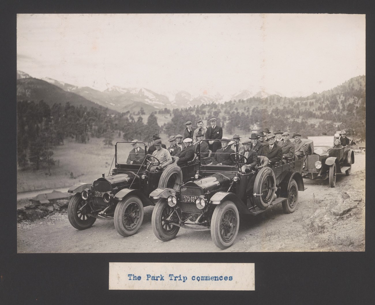 Three old, open-top touring cars full of men