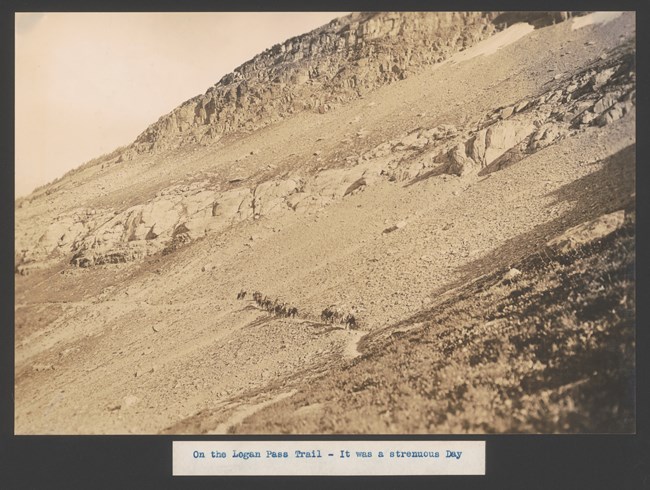 A line of people on horseback go up a mountain pass