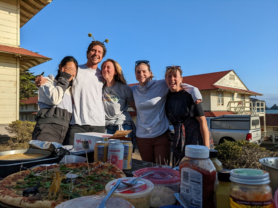 photo05_BotanyOlympics_AlexIwaki Five Botany Team members gathered for a silly group photo behind a picnic table covered with food and condiments.