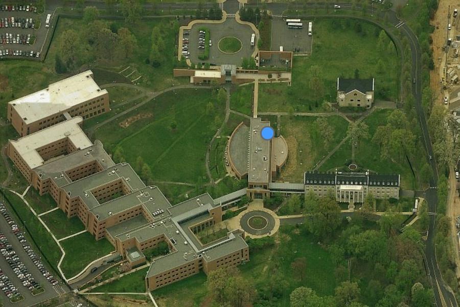 Aerial view of Arlington Hall today, State Dept. Training Center. There are buildings that connect to a main building and parking lots surrounding them.
