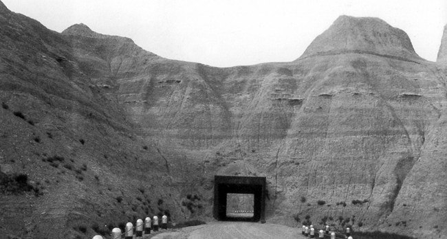 a square tunnel bores through thick badlands formations.