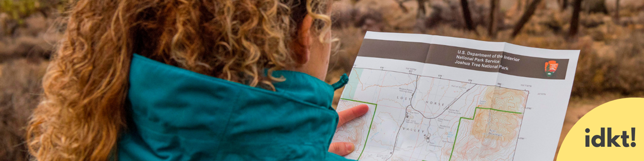 Plan Ahead and Prepare a person with their back to the camera examines a map in Joshua Tree National Park