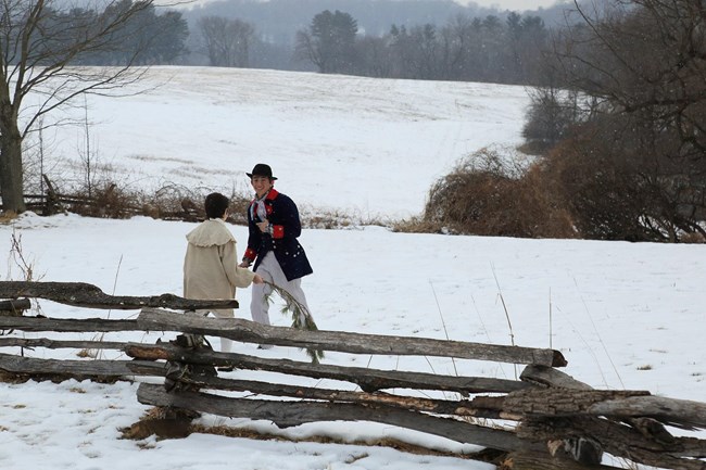 two children in historical dress play in the snow