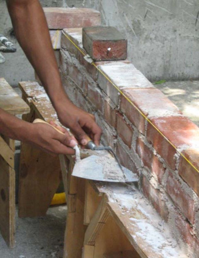 A student repointing a masonry wall.