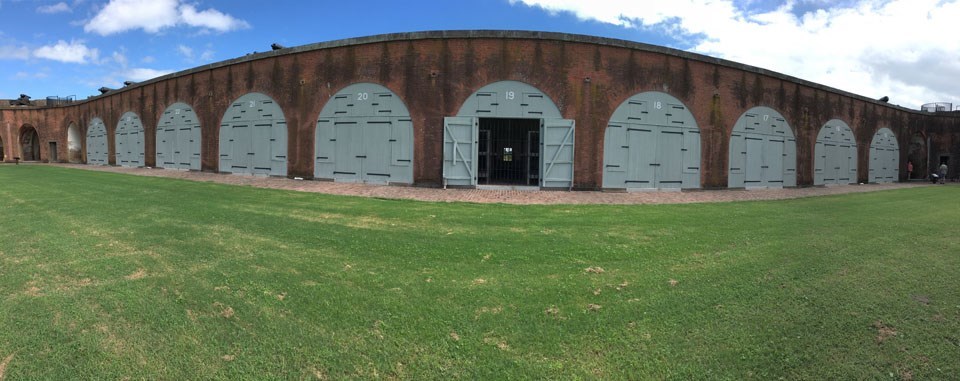 panoramic view of fort wall open casemate with iron bars flanked by closed casemates