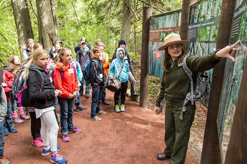 a uniformed NPS ranger points at a sign while leading a program