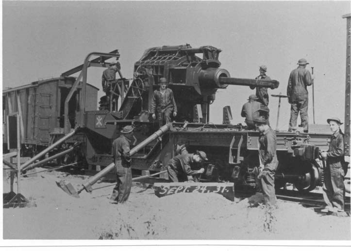 a group of men gather around the Battery C 12-inch mortar