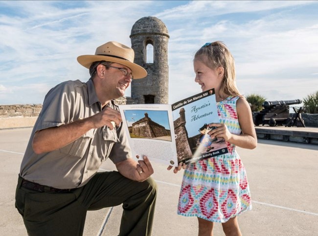 Park Ranger and Junior Ranger pose on the fort's gun deck.