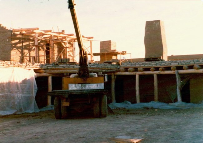 A truck is next to an adobe walled structure under construction.