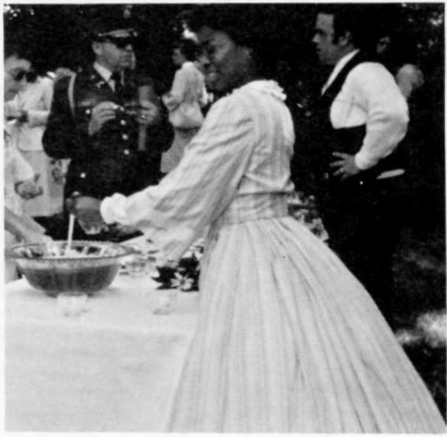 Regina Jones dressed in a Civil War era dress serves punch from a punch bowl.