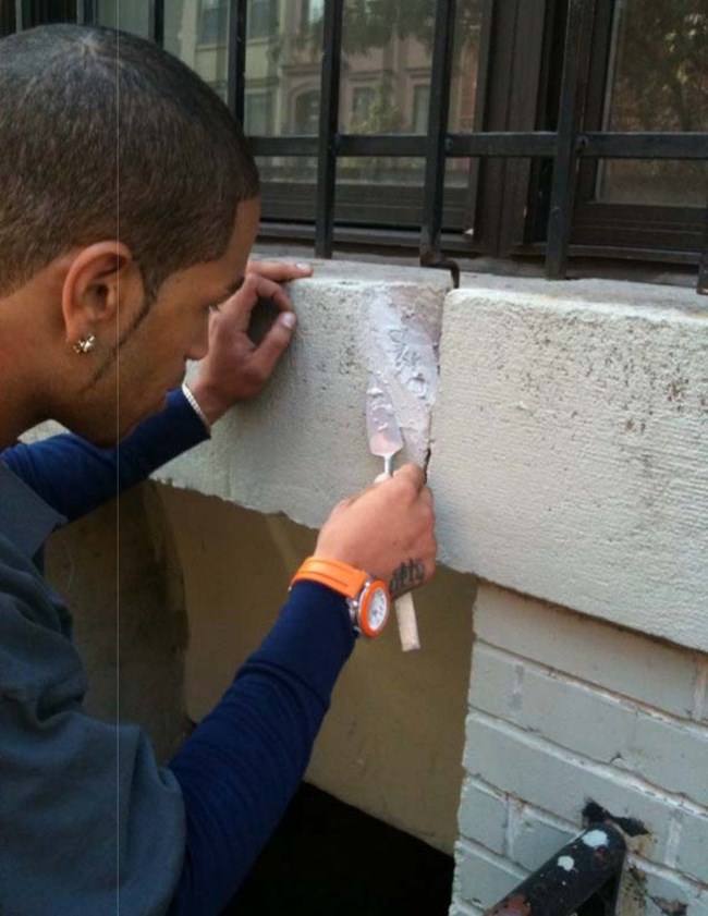 Student repairing a gap with mortar.