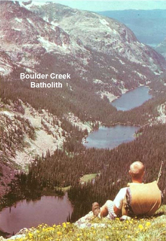 a person on a mountain side with a chain of lakes in a glacial valley below