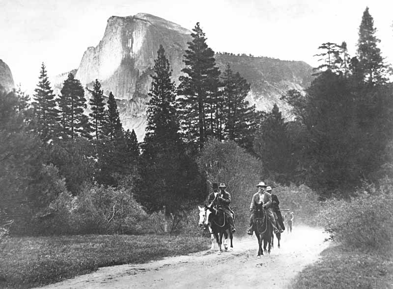 Four figures, including Theodore Roosevelt and John Muir, ride on horseback along a trail in the forest, with Yosemite's Half Dome in the background