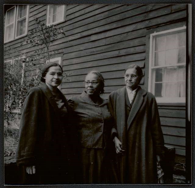 Three women standing outside a wooden building