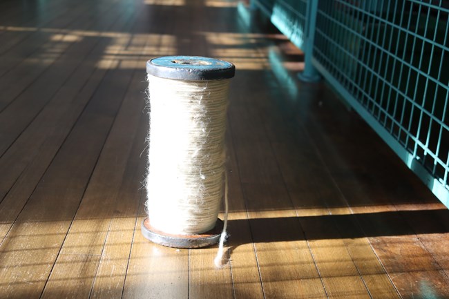 roving A large roll of thick yarn like cotton material placed on a wooden floor