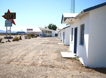 Dirt lot in front of a historic one-story motel.