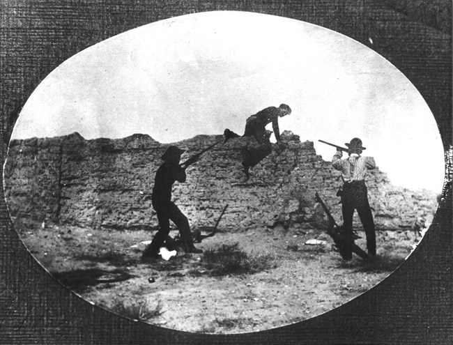 Men with rifles play next to the remains of a wall
