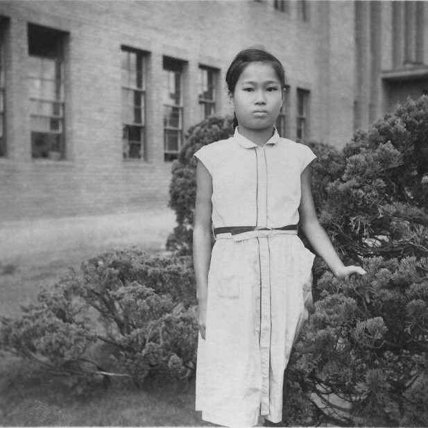A young Japanese girl wearing all white standing in front of a hospital