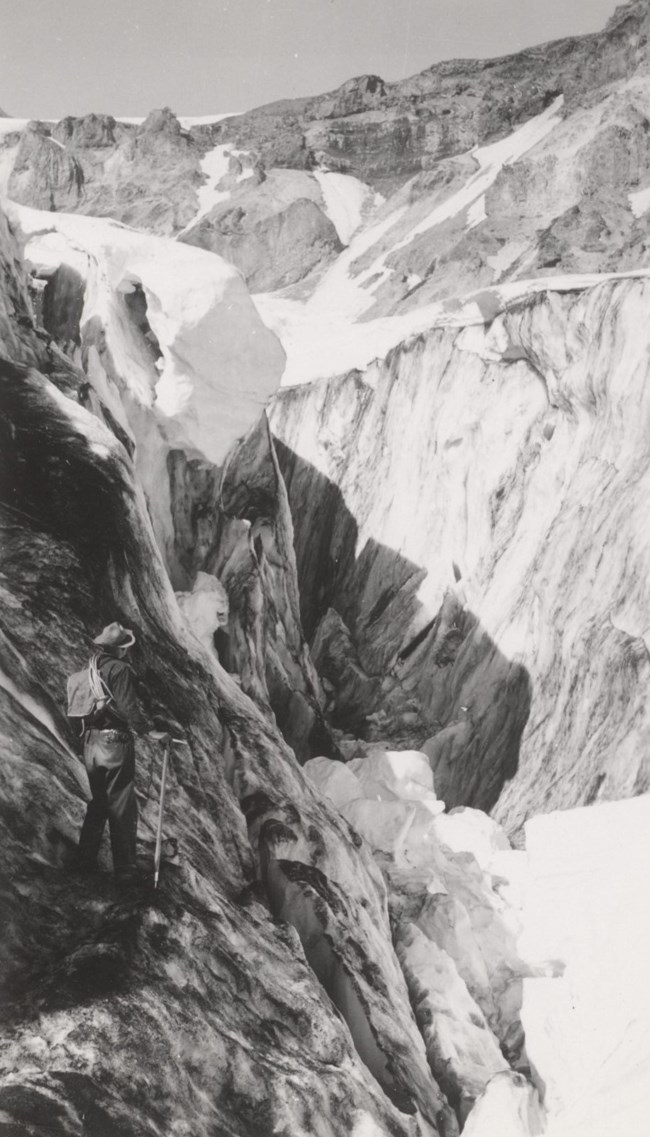 Man stands looking at a glacier and crevasses