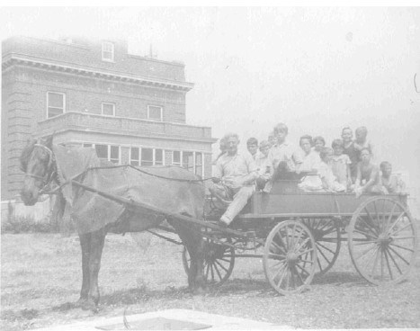 a group of school children sit in a wagon pulled by a horse