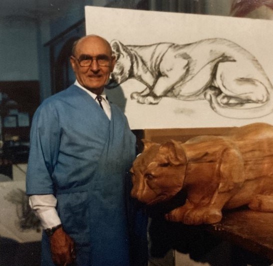 John Segeren with his carved cougar. John Segeren standing next to a carved wooden cougar