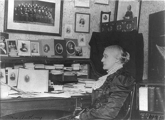Susan B Anthony seated at desk.