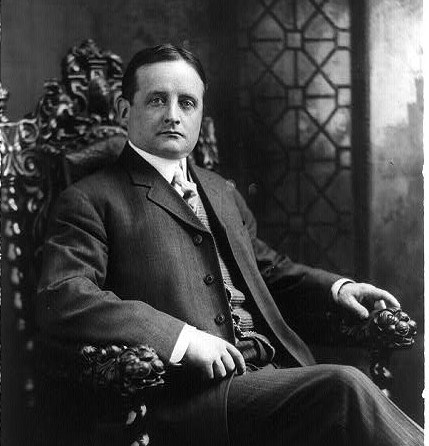 A black and white photo of John F. Fitzgerald seated in an ornate wooden chair with a leather seat.