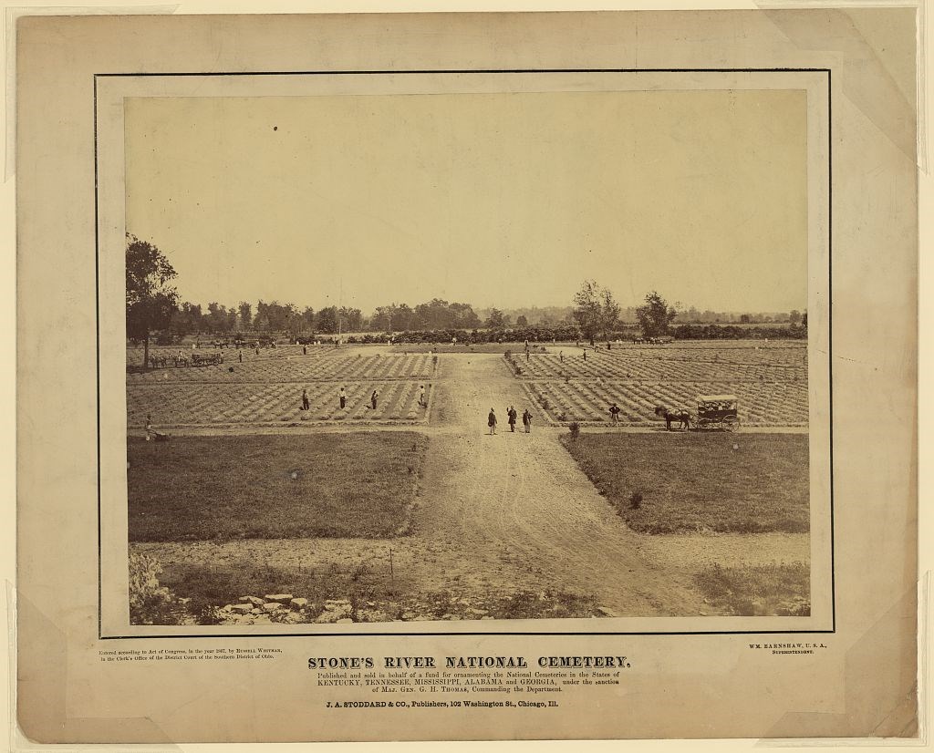 People, some with shovels, and a horse-drawn cart scatter across a landscape where broad walkways divide rows of burials.