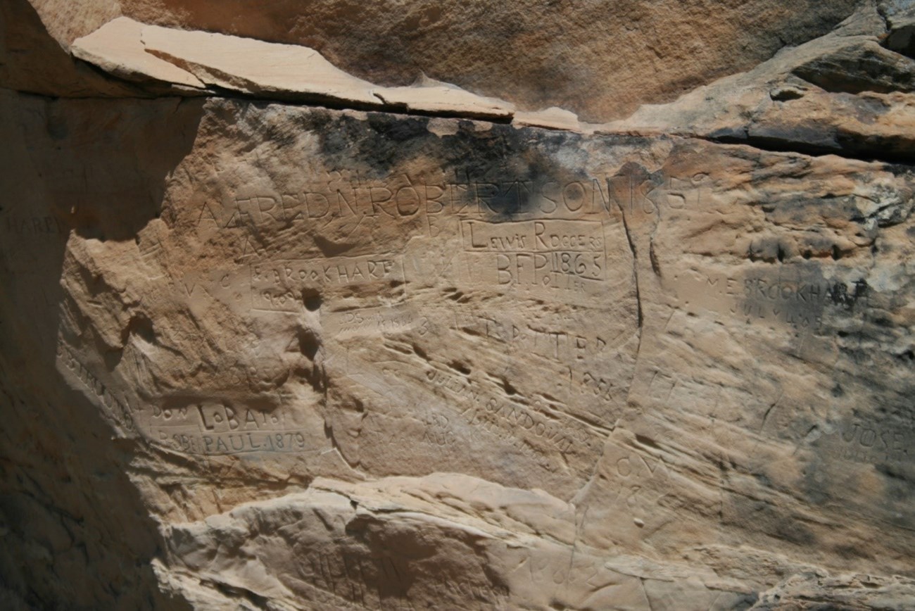 Rock formation with names and dates carved into it.