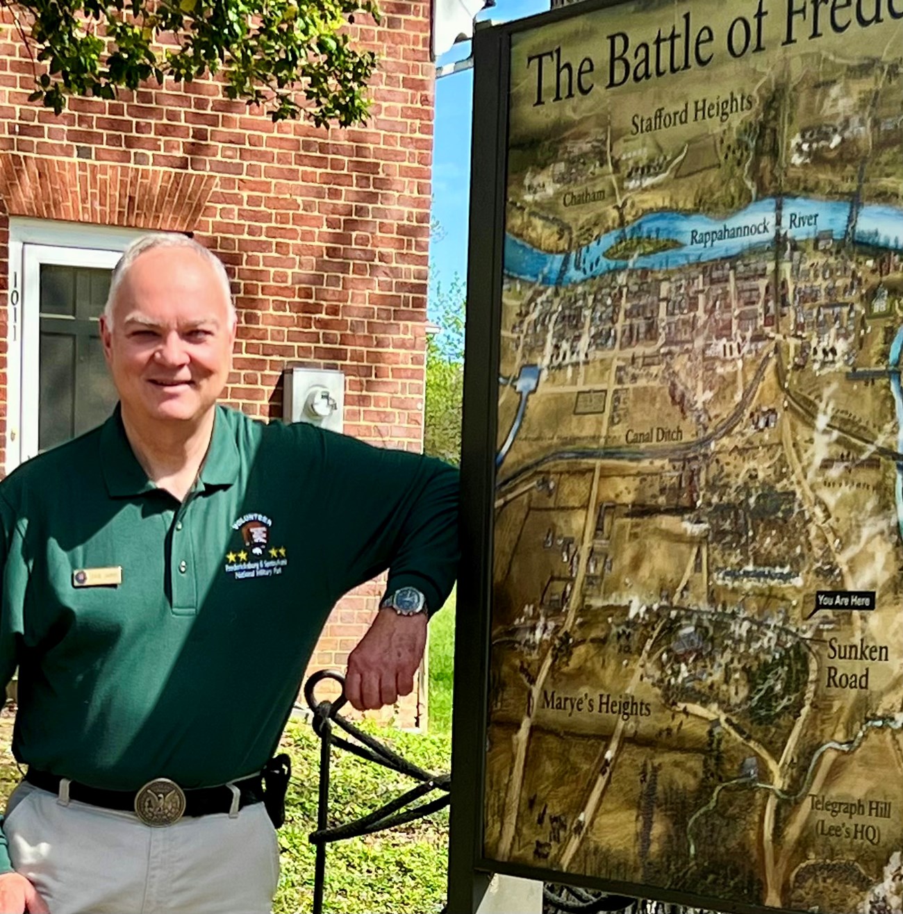 David James Fredericksburg and Spotsylvania National Military Park volunteer poses next to the outdoor battle map of the Battle of Fredericksburg.