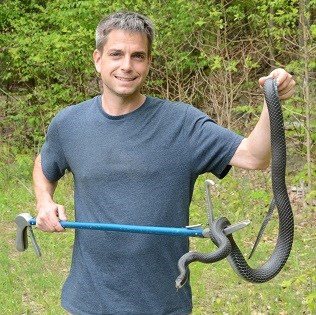 Dennis Quinn, surveyor of reptiles and amphibians, holds a black racer snake. Photo courtesy of Jani Quinn.