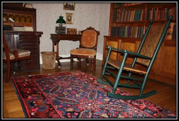 snuggery 2 a room with 2 bookcases on the walls and 2 wicker sitting chairs