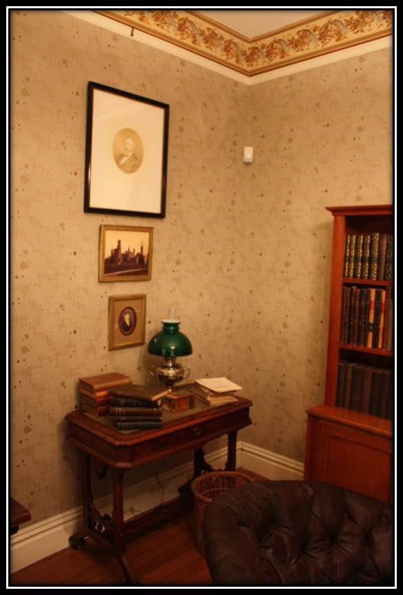 snuggery5 3 pictures hanging on the wall above a small table that has papers and a green lamp