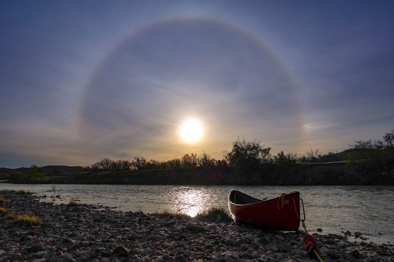 A crisp winter solstice sunrise over a river with a canoe in the foreground